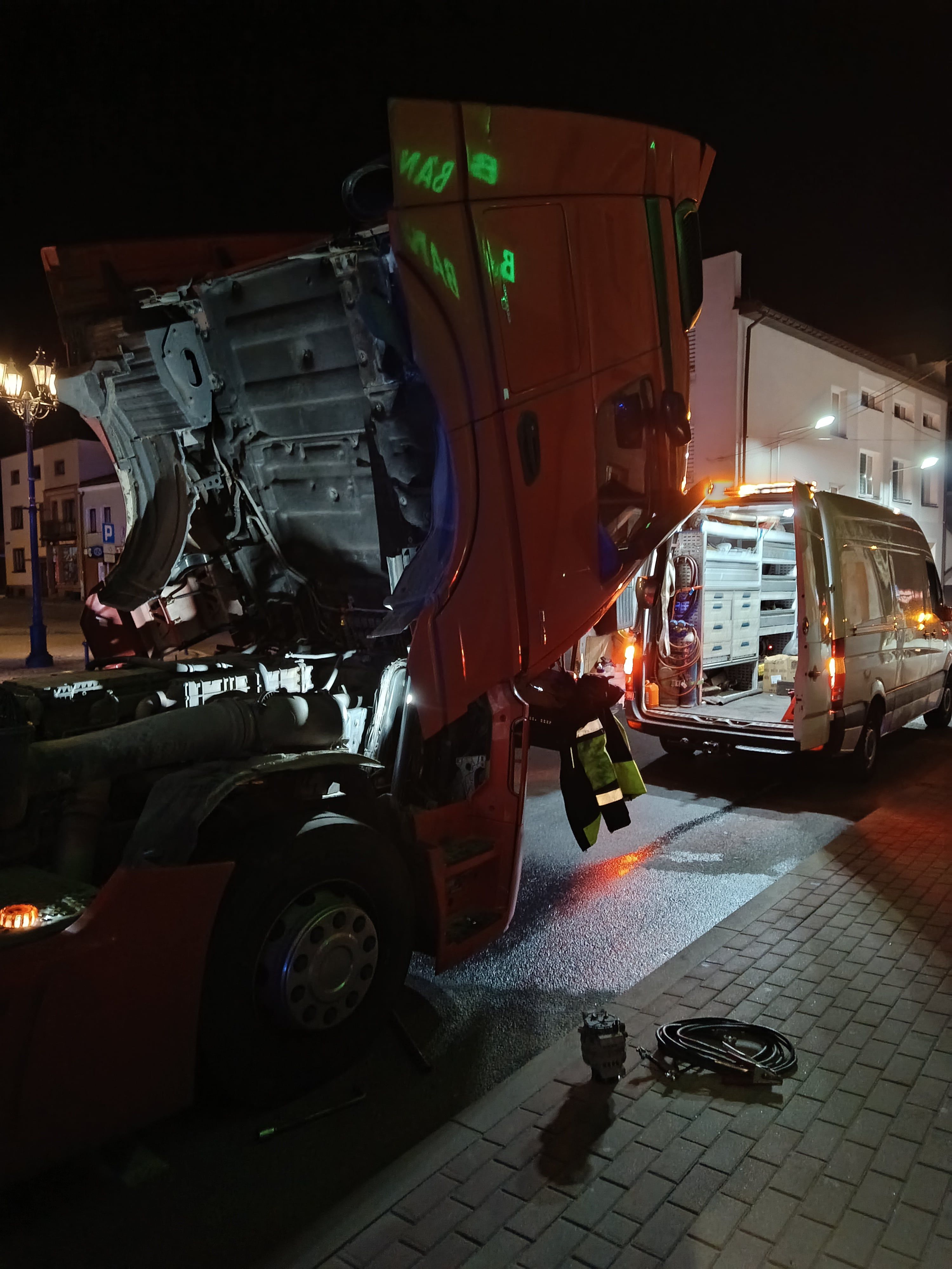 Naprawa czerwonego tira w terenie, zdemontowana chłodnica i w pełni wyposażony bus mobilnego serwisu ciężarówek
