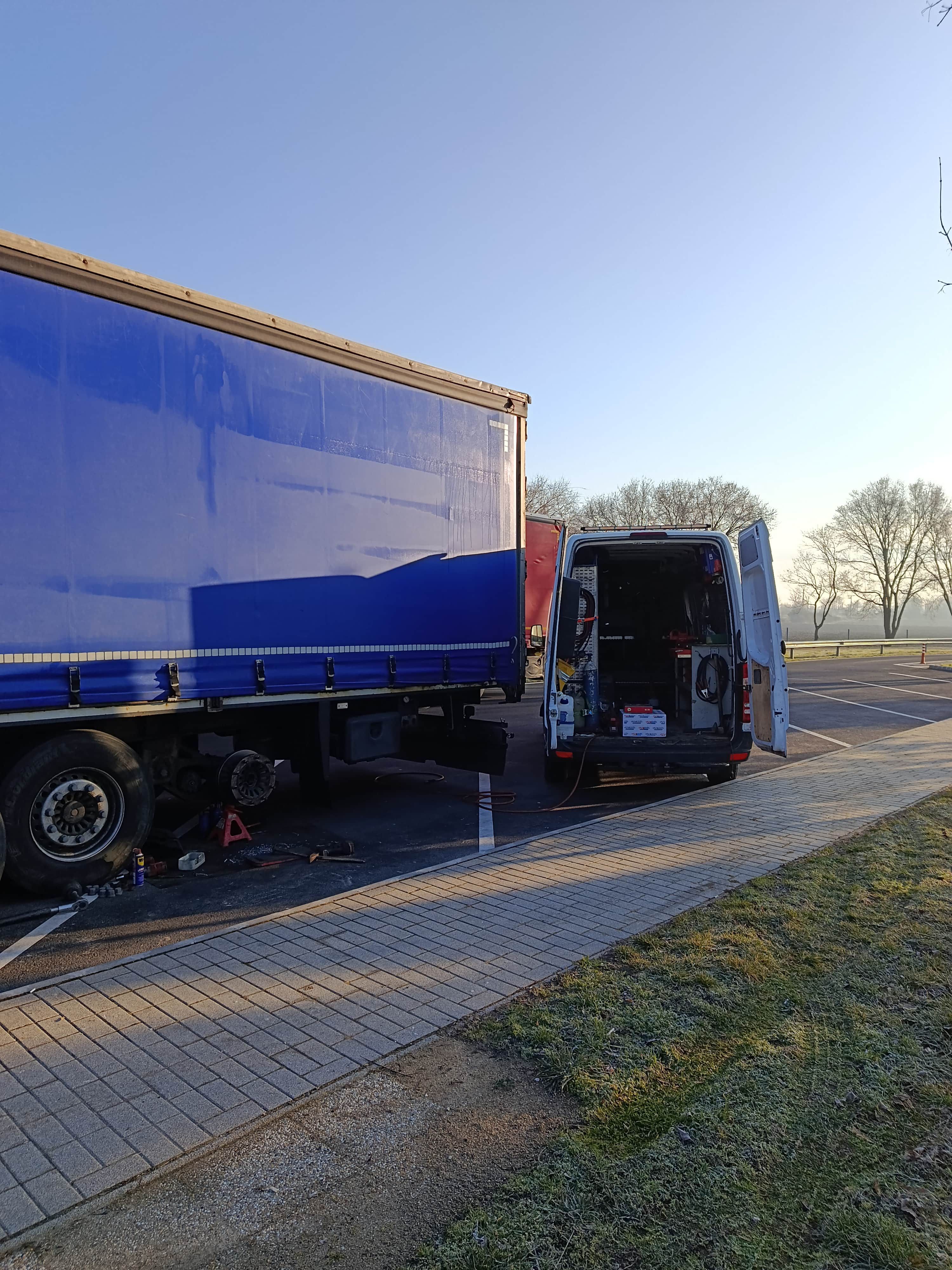 Profesjonalnie wyposażony bus mobilnego serwisu TIR z narzędziami podczas naprawy czerwonej ciężarówki Scania z podniesioną kabiną