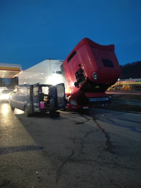 Technik mobilnego serwisu pracujący przy czerwonej ciężarówce o zmierzchu.